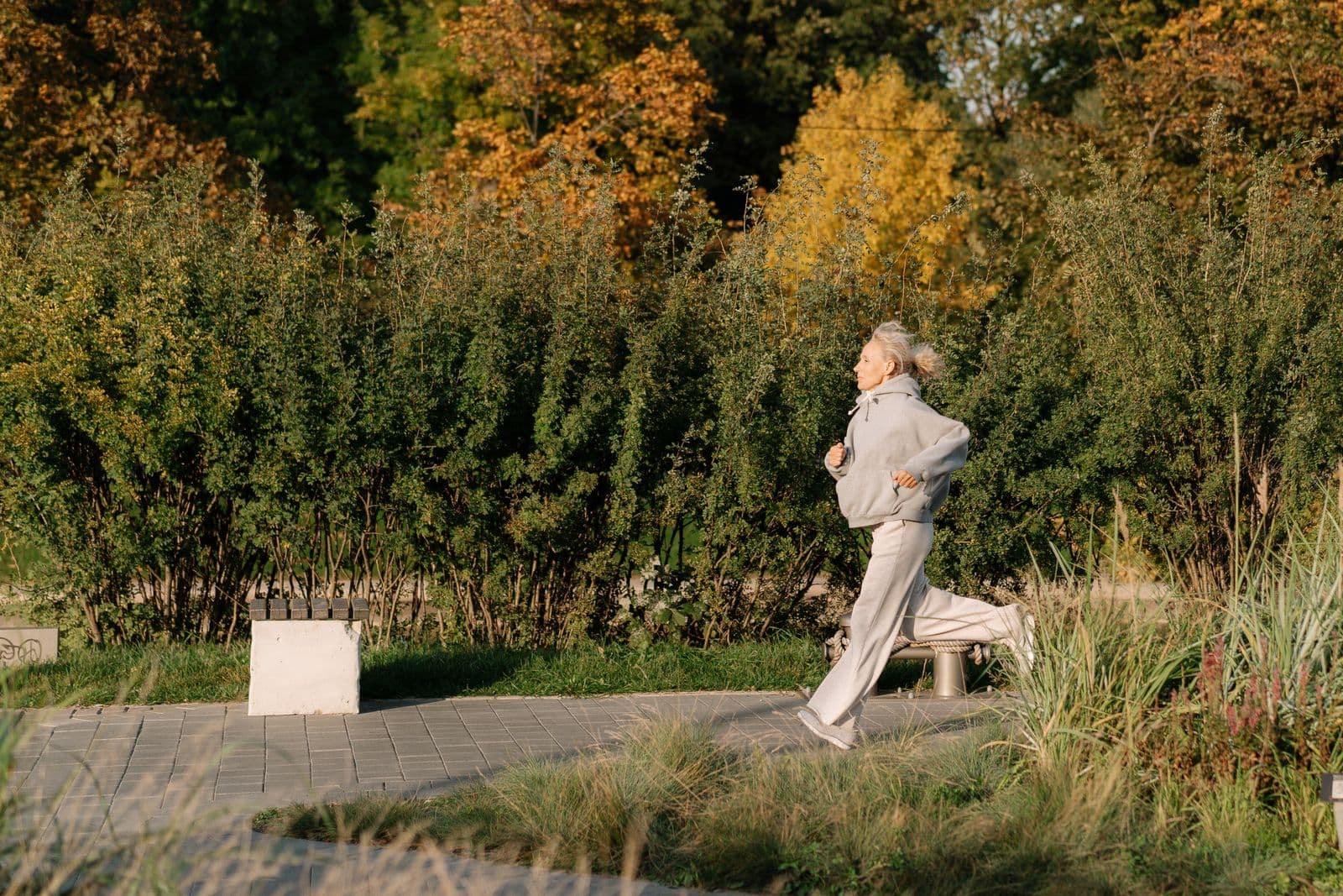 A woman jogging through a park in golden light